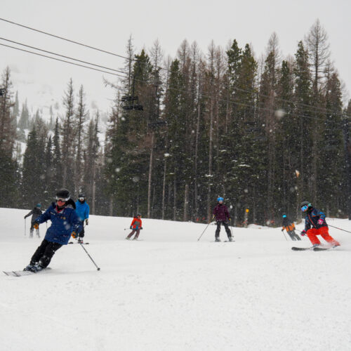A ski instructor is followed down a piste by his students at Mission Ridge.