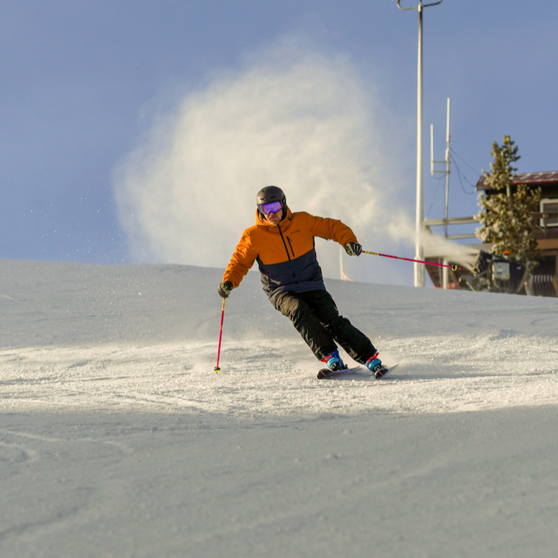A skier descends the sunspot trail at Mission Ridge with a snow gun in the background.
