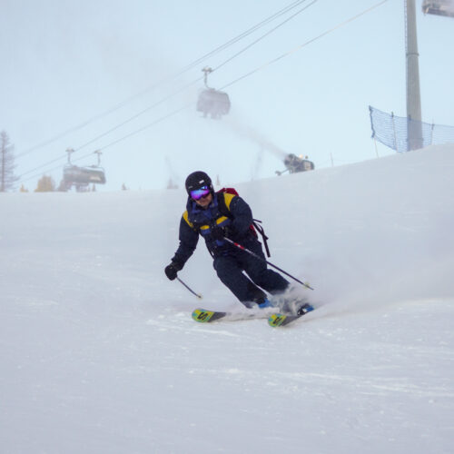 a man skis through snowmaking snow on a sunny day