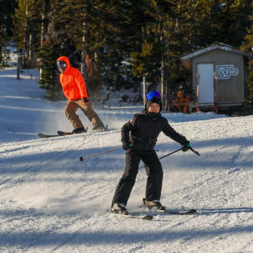 a child and father ski on a sunny slope