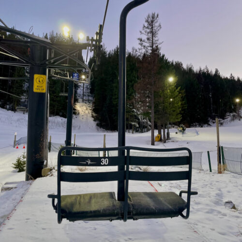 A chairlift chair hanging from the line with a nighttime Mountain View in the background
