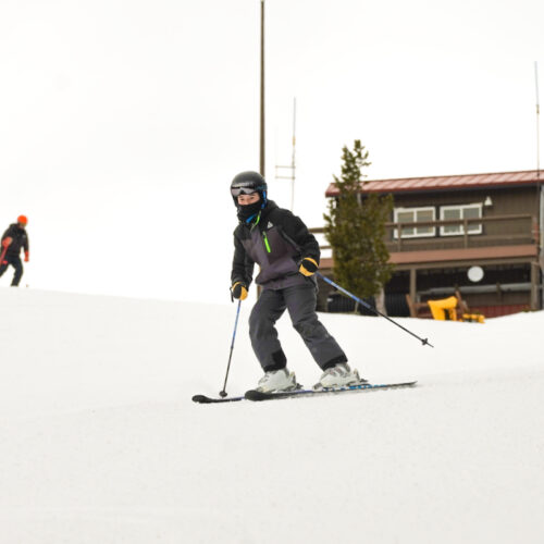 A young skiers decesnds the Sunspot trail at Mission ridge, with the patrol shack in the background.