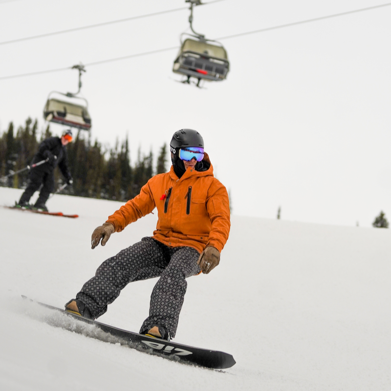A snowboarder descends the Tumwater trail at Mission Ridge with chair 2 in the background.