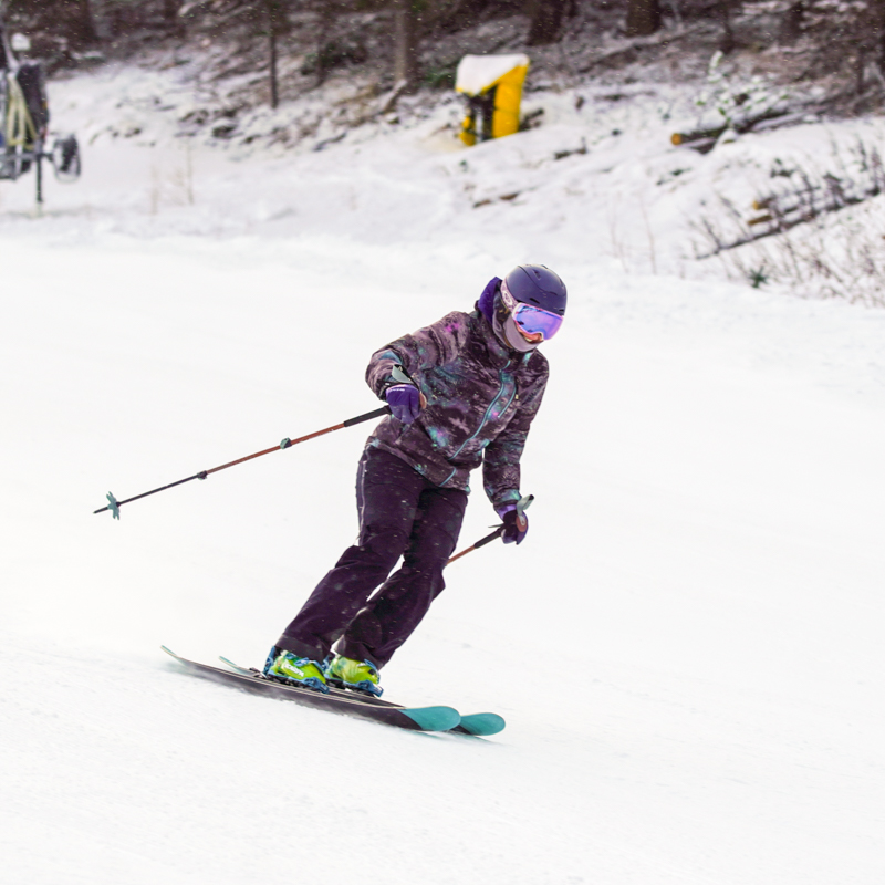 A woman smiles as she skis an overcast slope