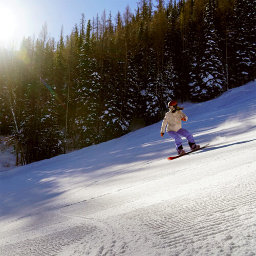A female snowboarder making a heel side turn
