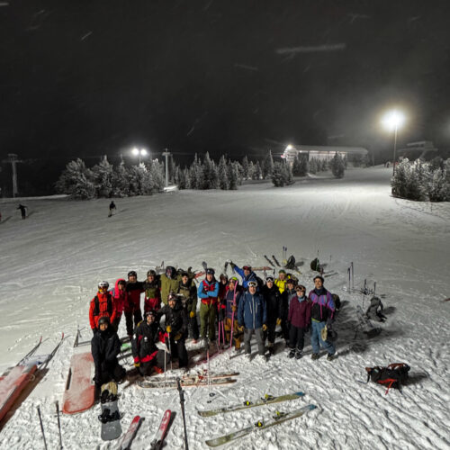 Group of touring skiers posing in celebration after making it to the top of Mission Ridge at night.