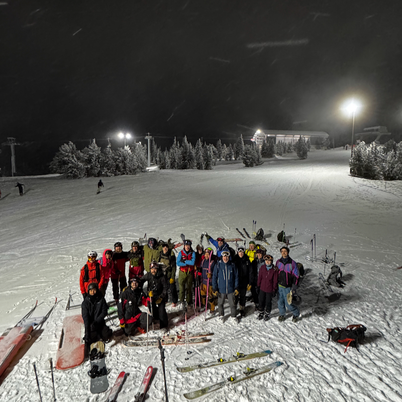 Group of touring skiers posing in celebration after making it to the top of Mission Ridge at night.