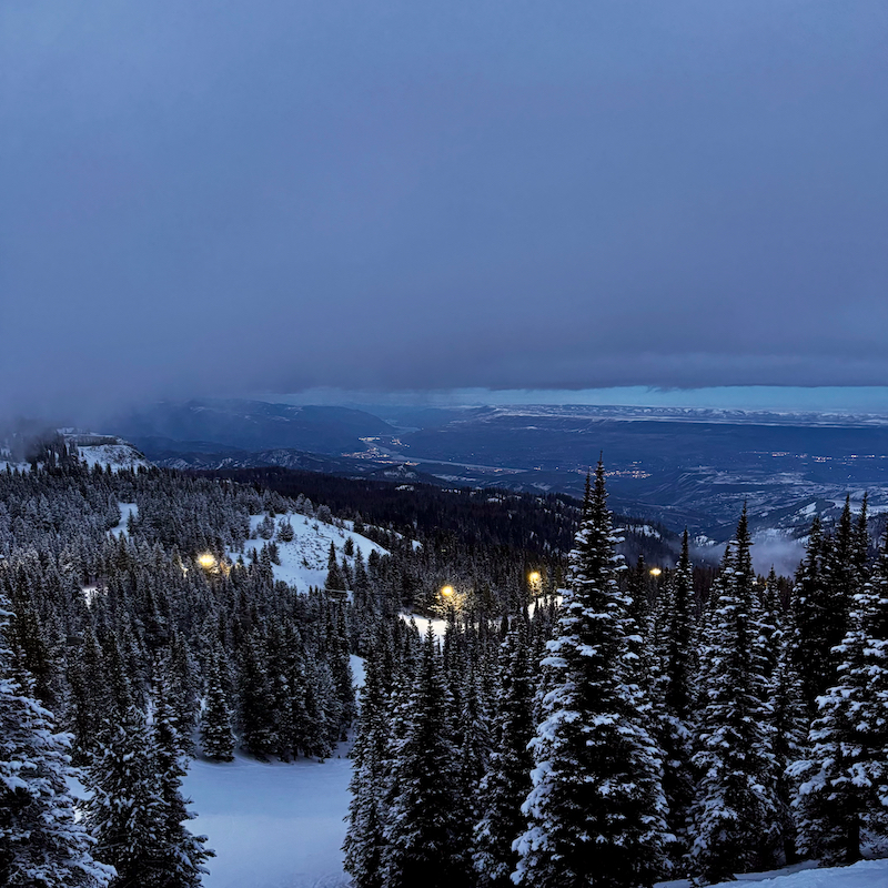 A snowy mountainside with night skiing lights at night.