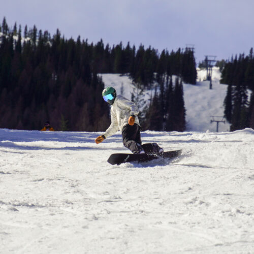A snowboarder descends the Mimi trail at Mission Ridge on a sunny day.