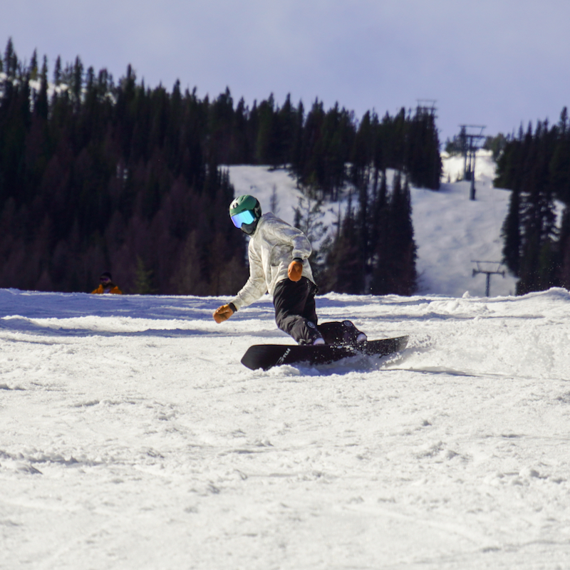 A snowboarder descends the Mimi trail at Mission Ridge on a sunny day.