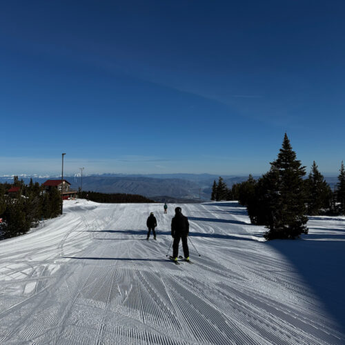 Skiers prepare to descend the Sunspot trail at Mission Ridge on a sunny day.