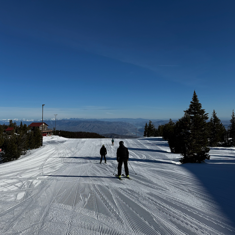 Skiers prepare to descend the Sunspot trail at Mission Ridge on a sunny day.