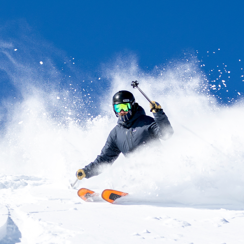 A skier slashes into a pow stash on a bluebird day at mission ridge.