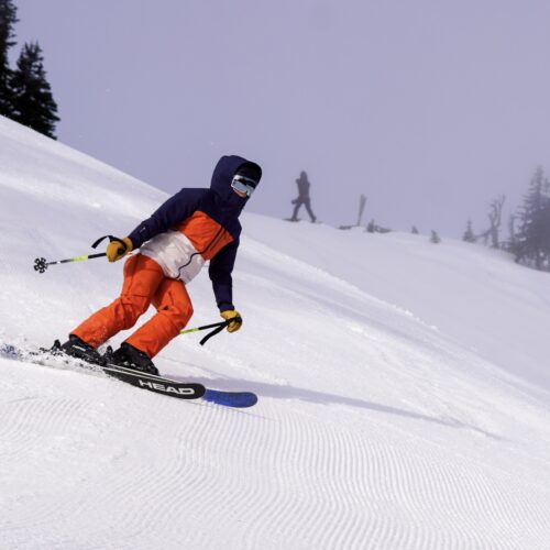 Orange skier sliding below yeti statue