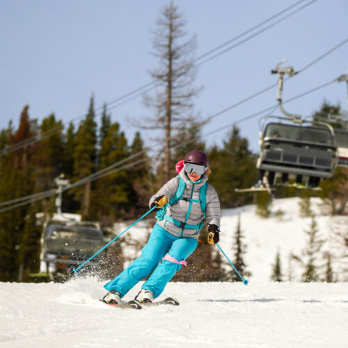 A skier in a grey and blue outfit descends the Tumwater Trail at Mission Ridge on a partly sunny day.