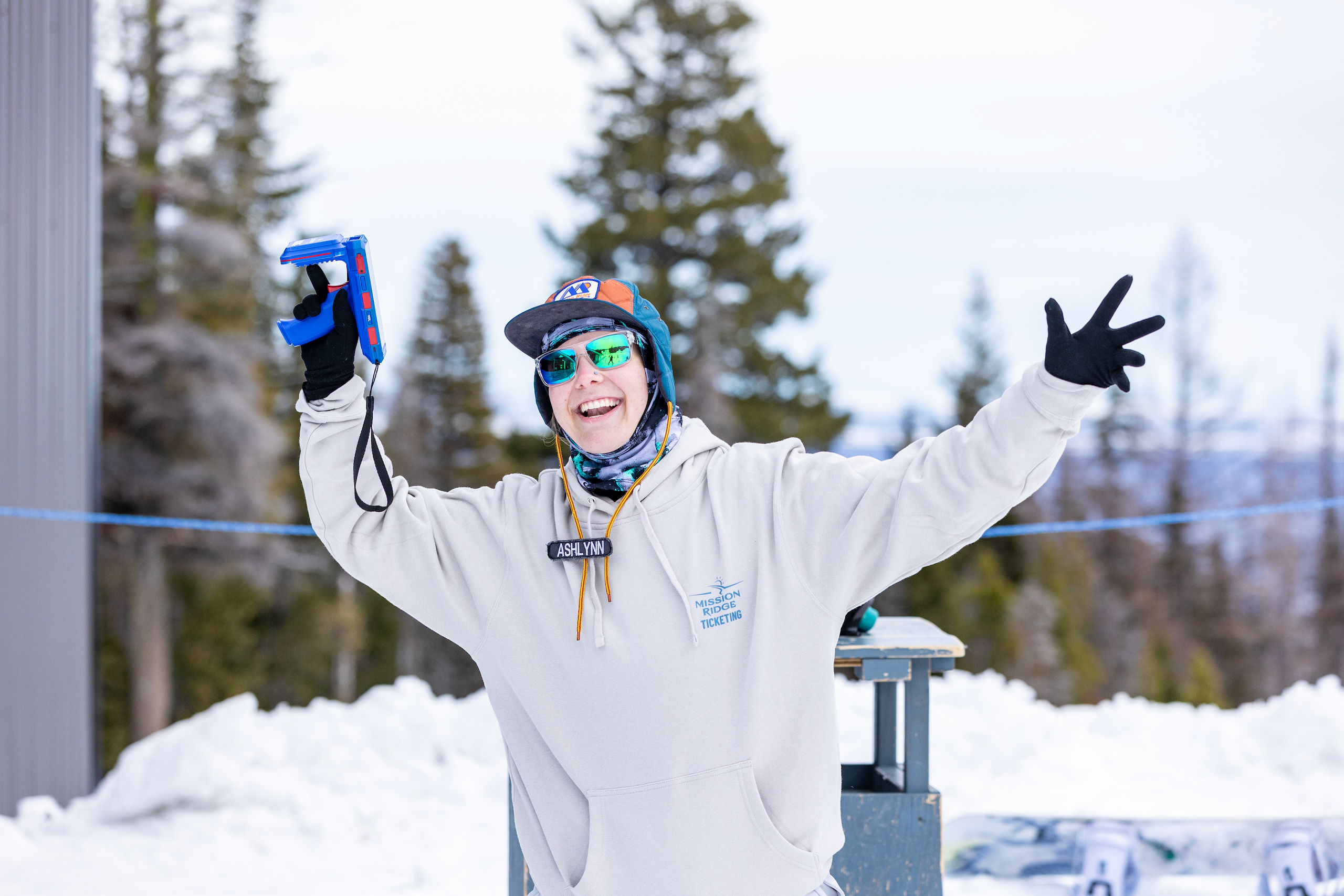 A Mission Ridge ticket scanner smiles and waves her arms to greet skiers.