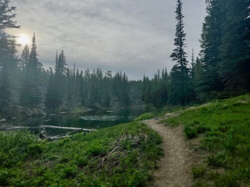 Dirt trail winds toward Lake Clara through an open meadow.