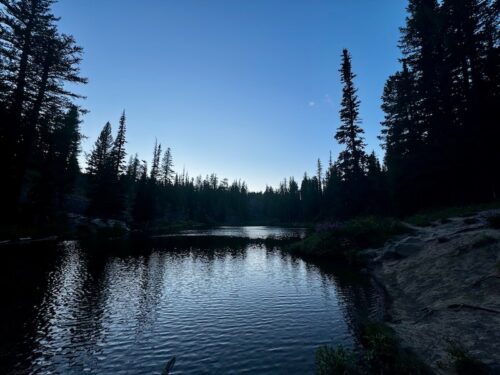 Lake Clara in the evening reflecting forest and dusky blue sky.