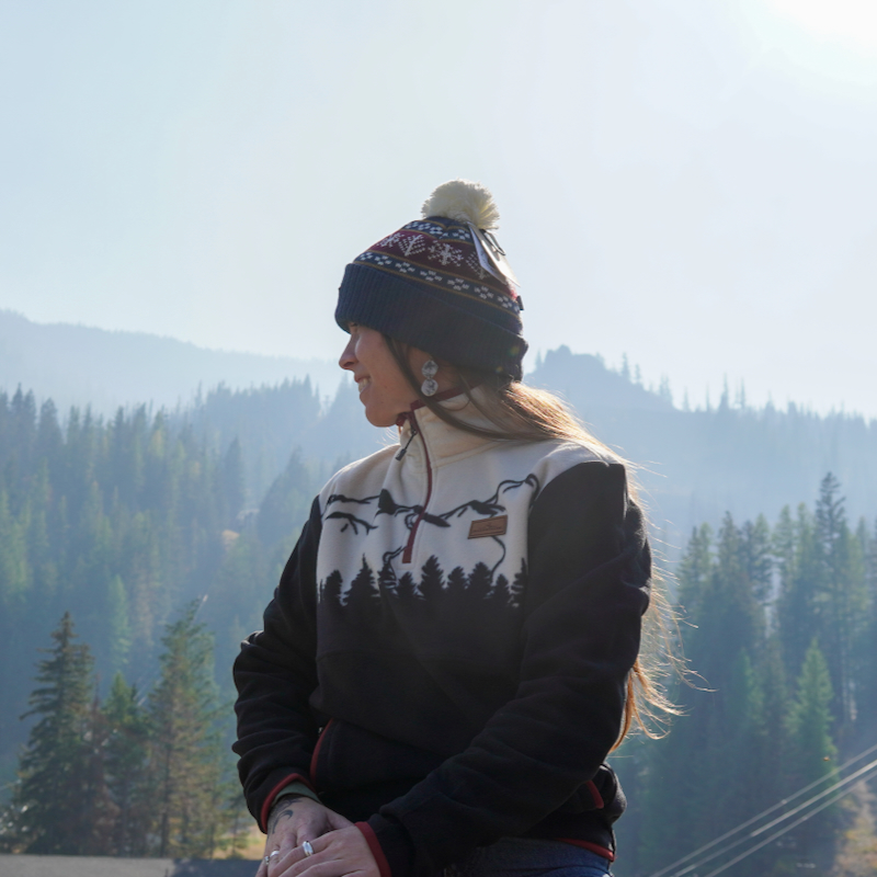 A person in a Mission Ridge beanie looking out over the mountains in fall